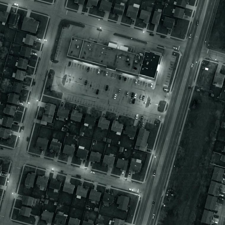 Grainy monochrome orbital image of a city block at night