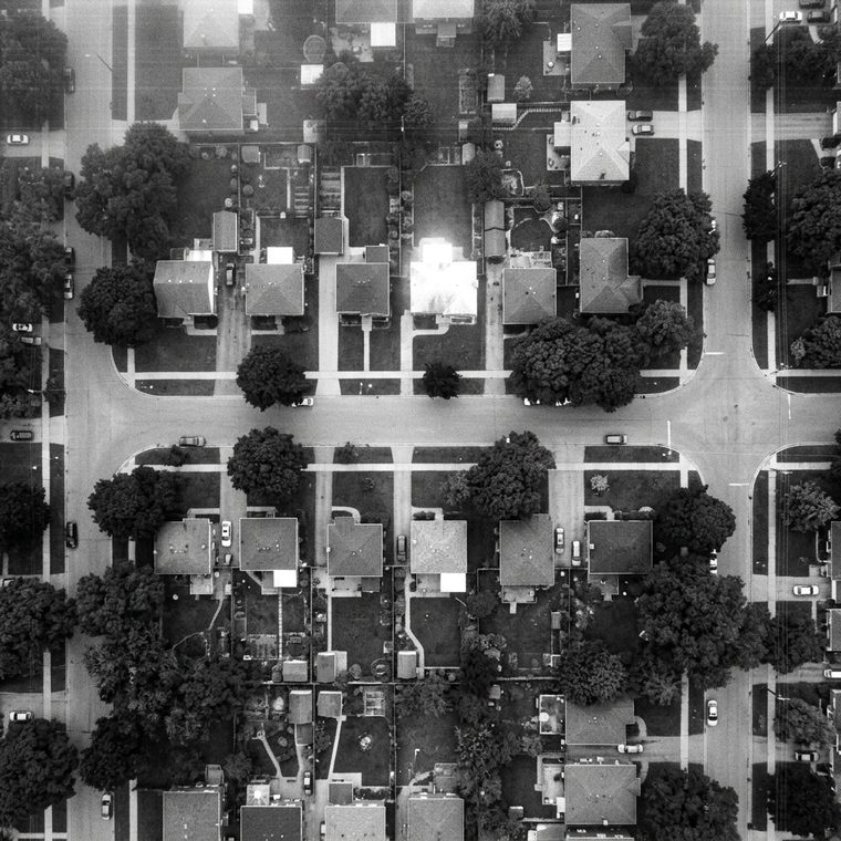 Monochrome overhead surveillance frame of a residential street of small houses and street trees