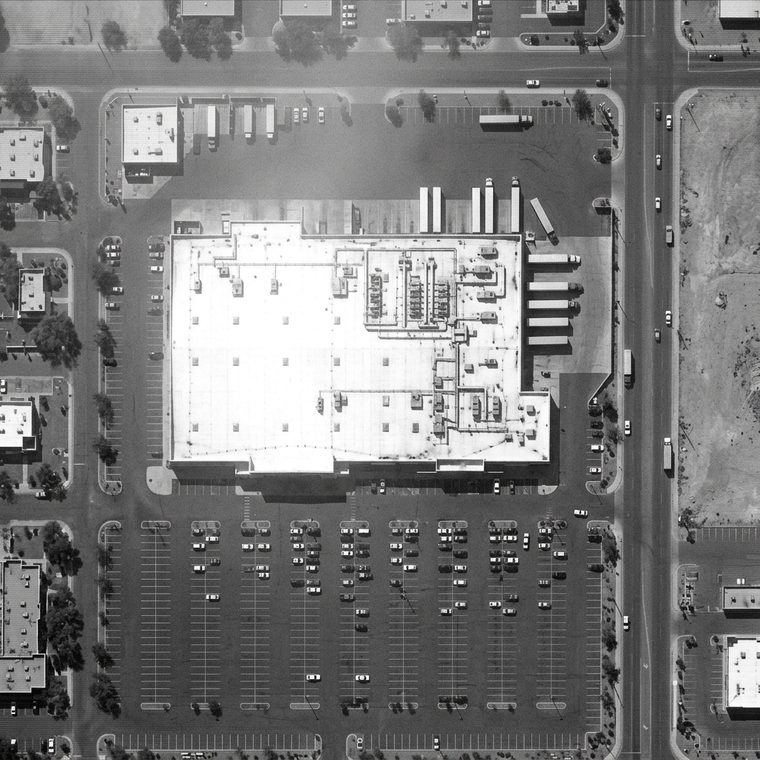 Monochrome overhead surveillance frame of a supermarket roof and its parking lot